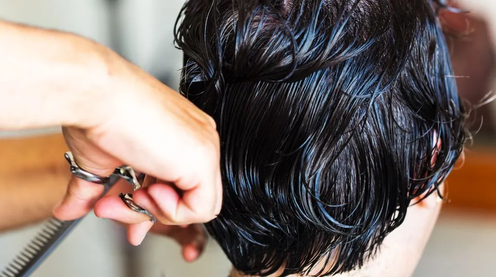 Scissors and comb working through dark hair, close up